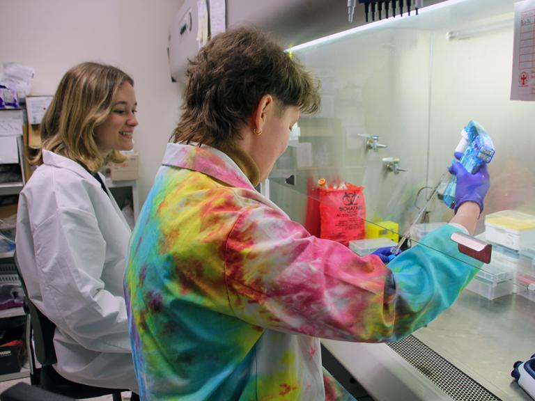 two trainees work at a hood in a lab